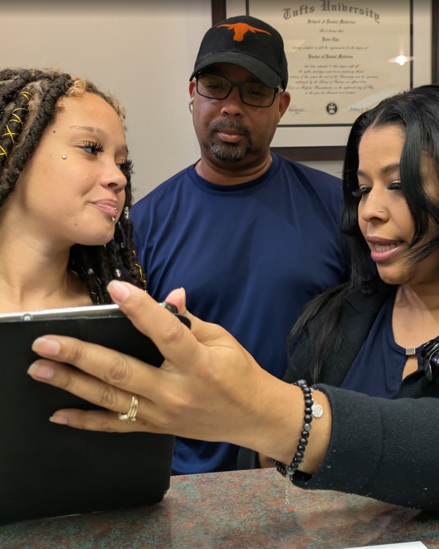 A patient and her father going over a tablet with the front desk