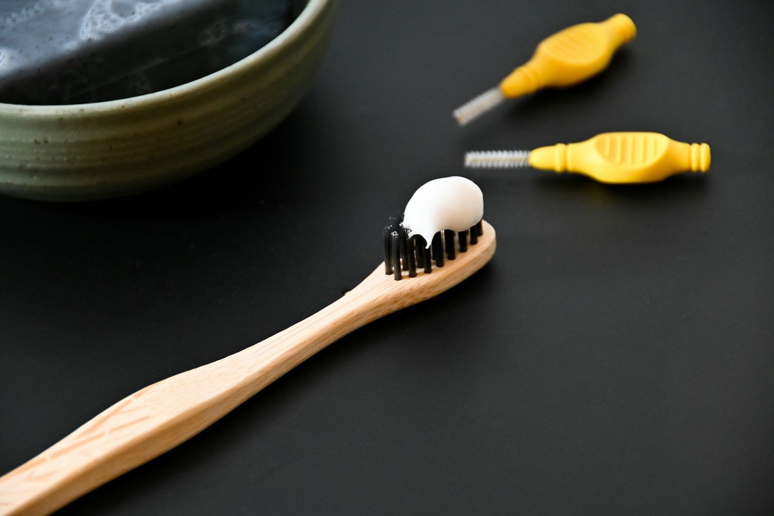 A toothbrush with paste and interdental brushes on black