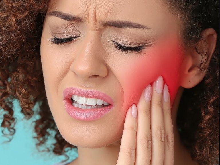 A woman grimacing and pressing her fingers to her jaw, with the sore area glowing red