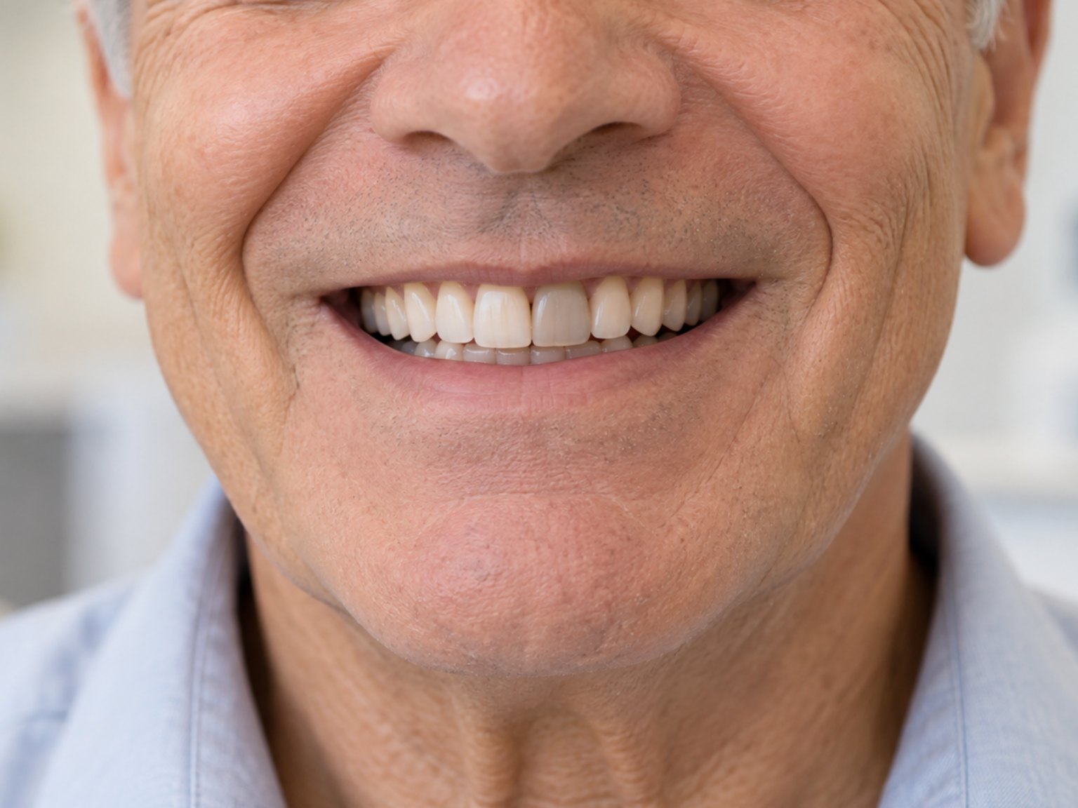 An older man smiling, one front tooth darker and greyer than the rest