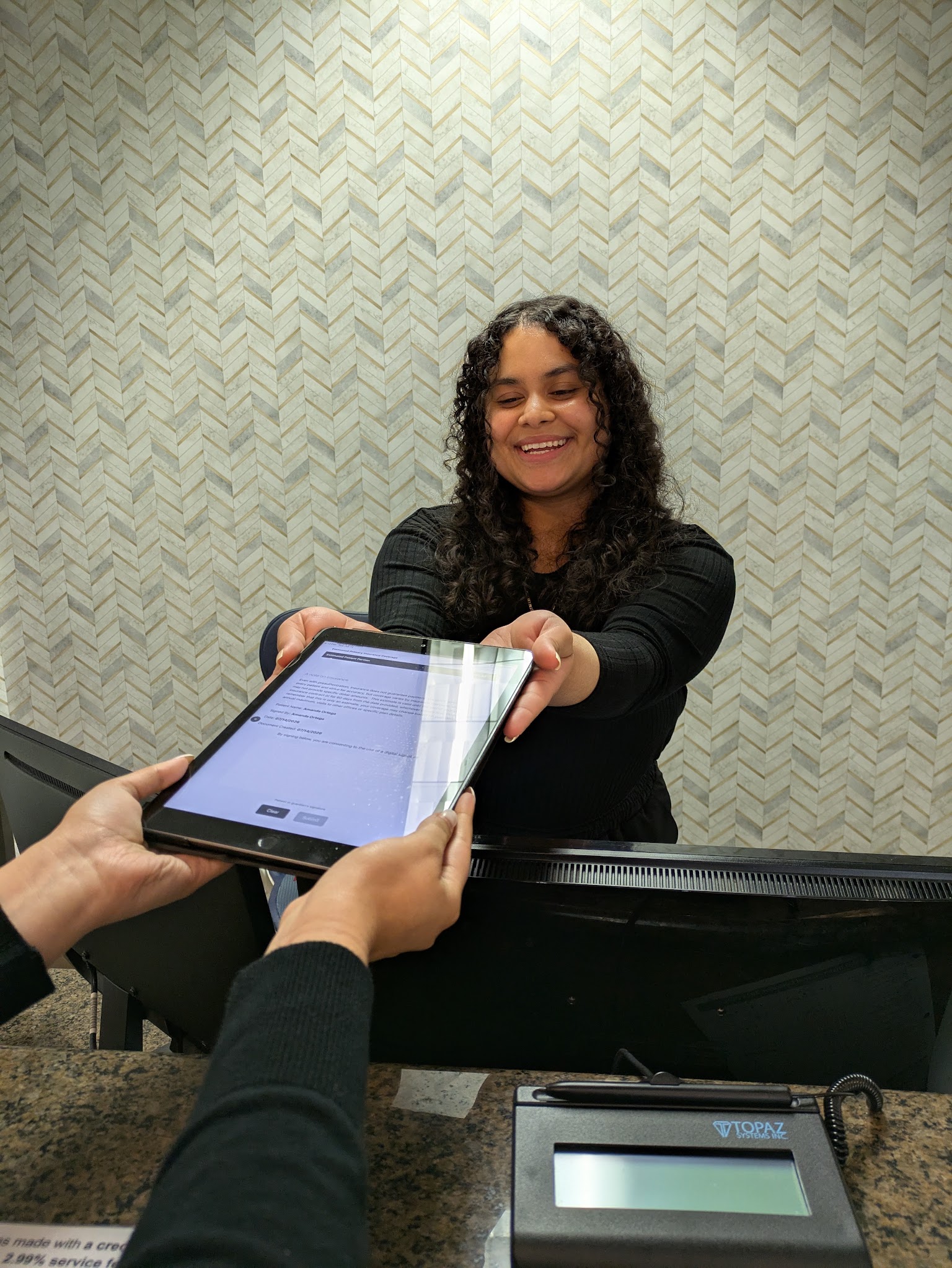 The front desk handing a tablet across the counter