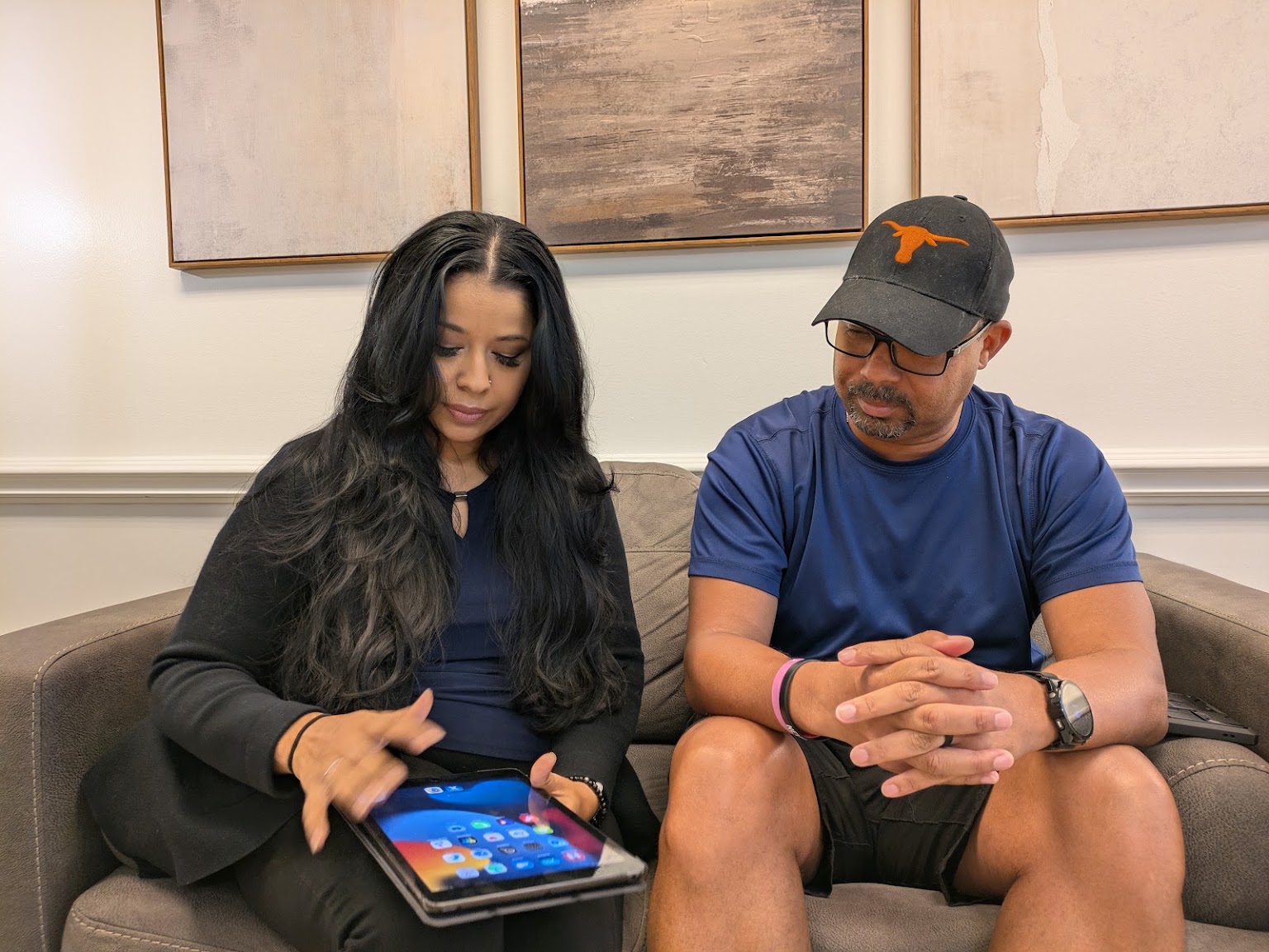 Two new patients on the waiting room sofa with the check-in tablet