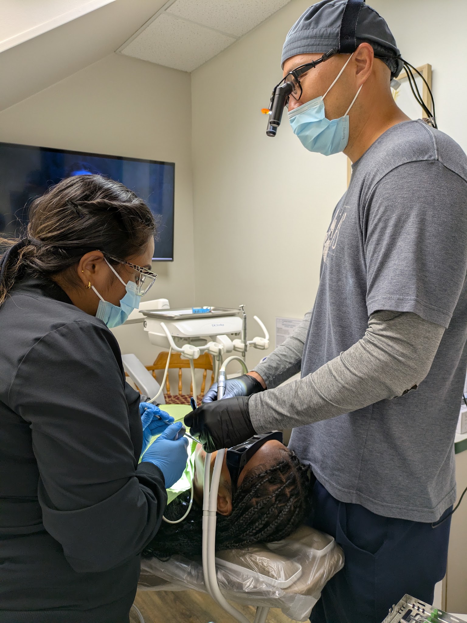 A dentist in loupes with his assistant at the chair
