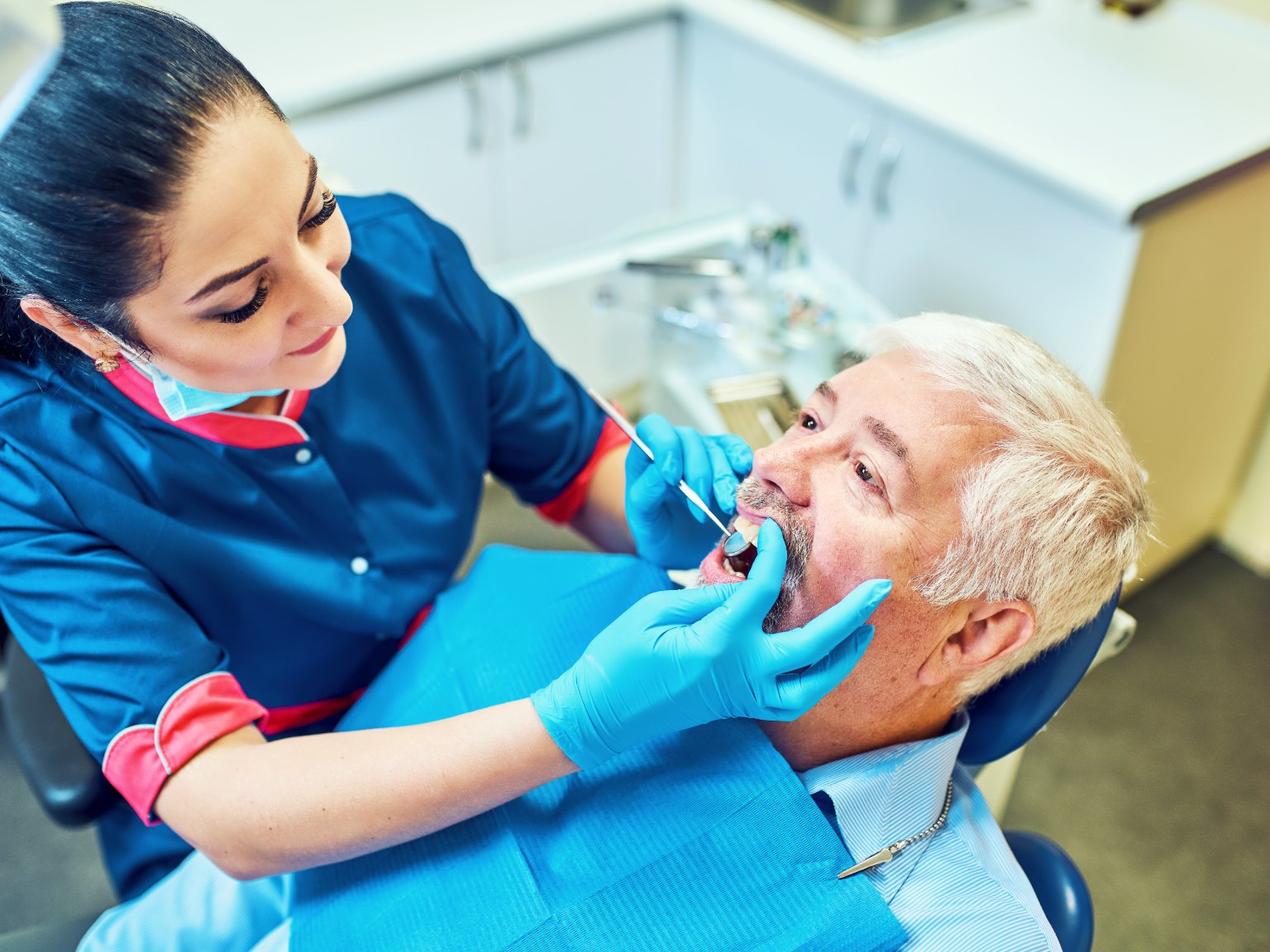 A dentist checking a patient's teeth and gums with a mouth mirror