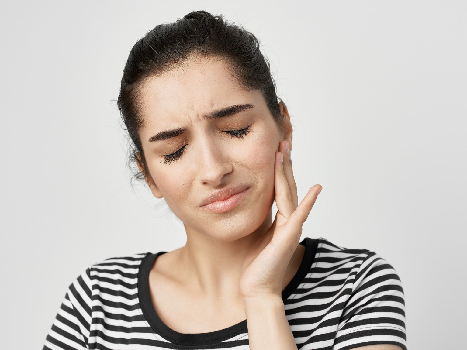 A woman pressing her hand to a sore jaw