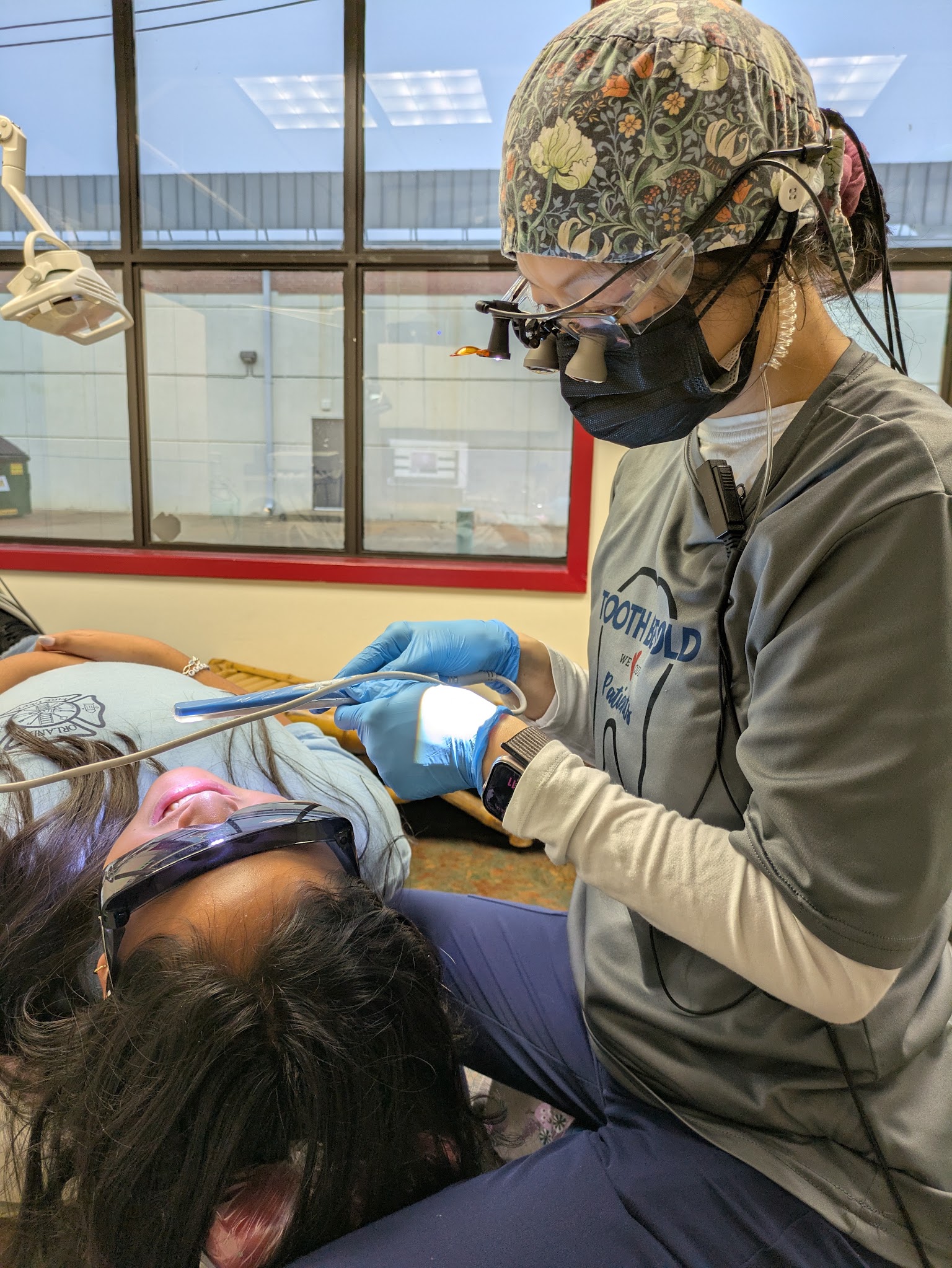 A hygienist in loupes at the chair with an adult patient
