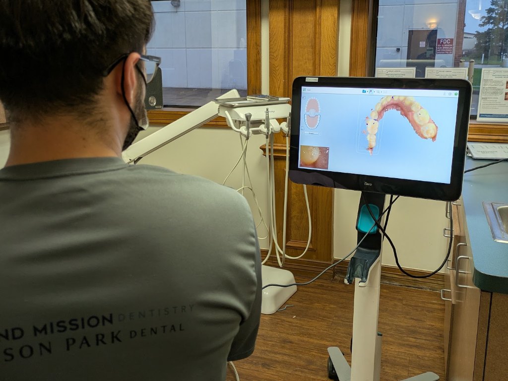 A clinician watching a 3D scan of a patient's lower arch on the scanner screen